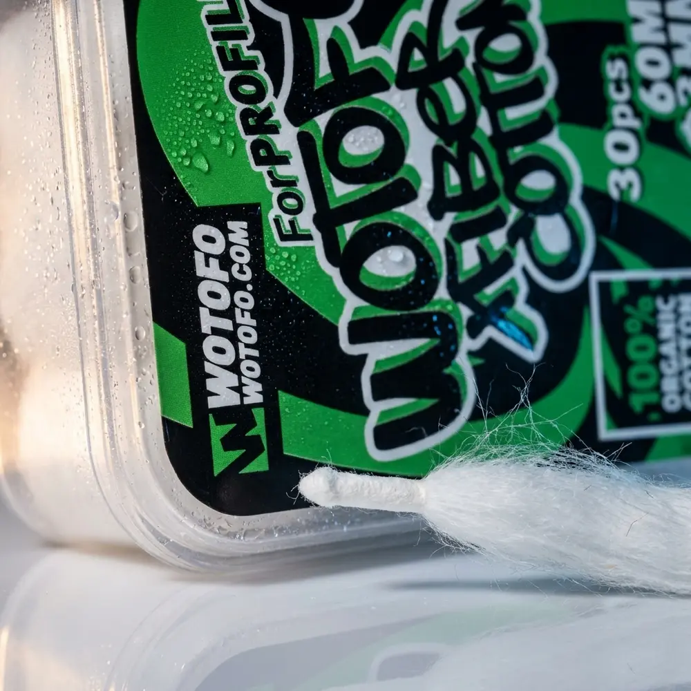 Close-up da ponta aglet do Algodão XFiber Wotofo mostrando fibras, textura da embalagem e gotículas - Vapor Gringo