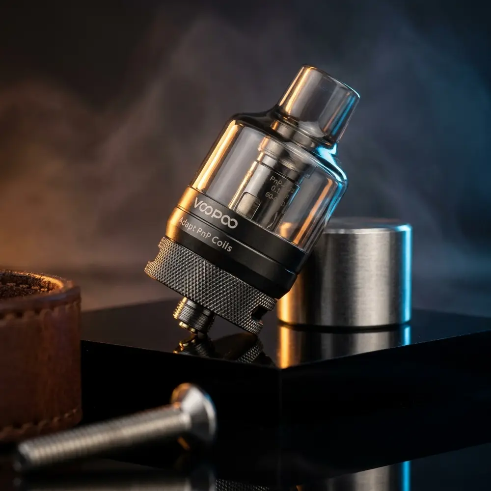 Atomizador PNP Pod Tank Voopoo sobre base acrílica preta, iluminação dramática azul e âmbar com reflexos metálicos - Vapor Gringo