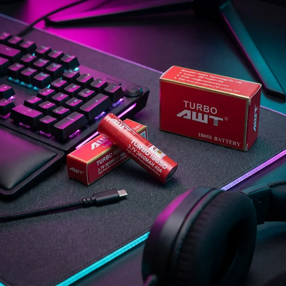 Bateria 18650 Turbo AWT sobre mesa gamer RGB, reflexos coloridos e objetos de estúdio ao redor - Vapor Gringo
