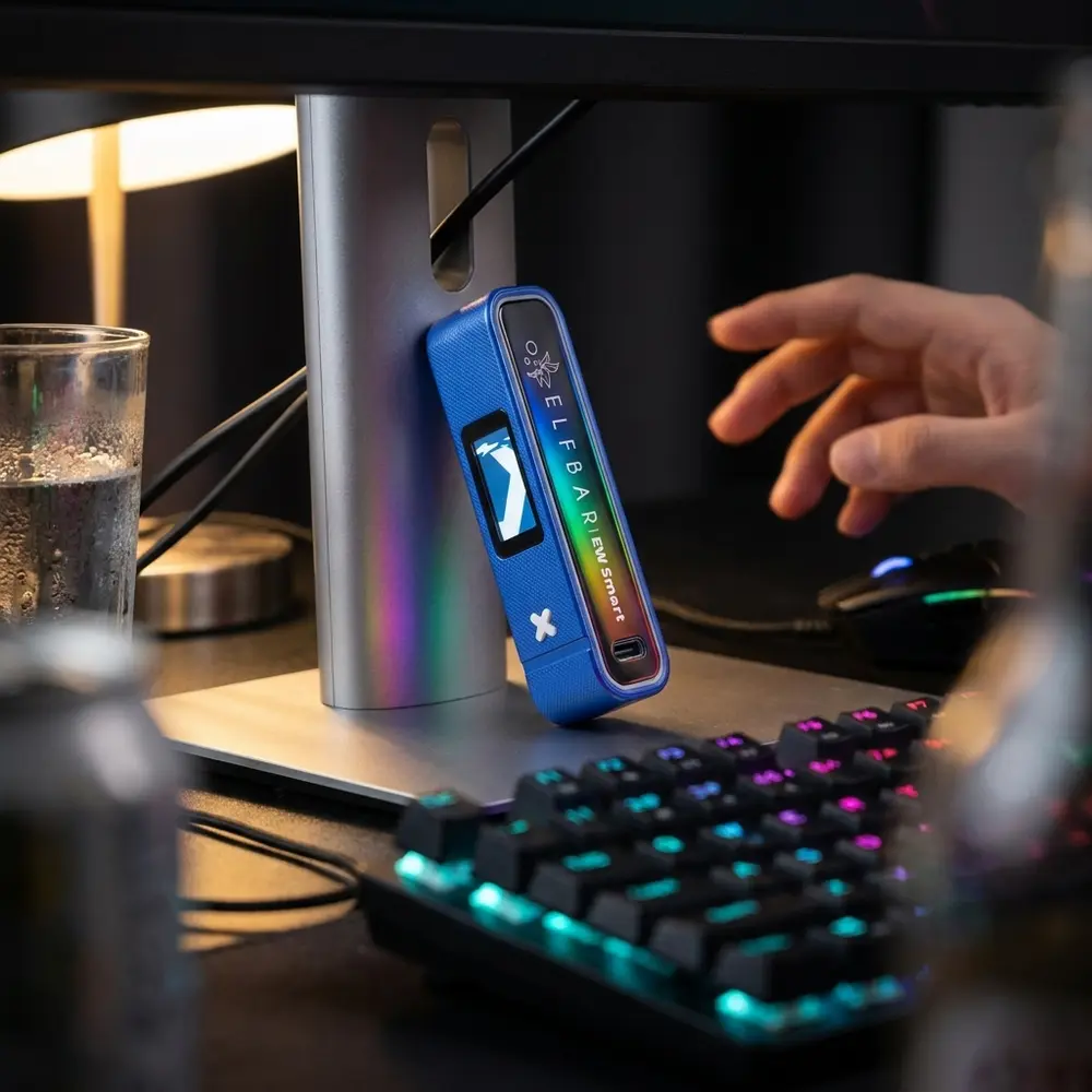 Bateria EW Smart Elf Bar apoiada em mesa gamer RGB, teclado e copo desfocados ao fundo - Vapor Gringo