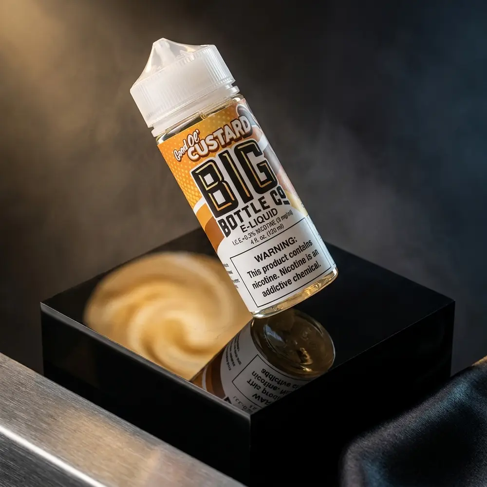Frasco Big Bottle Co. Good Ol' Custard 120ml em close publicitario sobre acrilico preto com reflexos cremosos e luzes quentes - Vapor Gringo