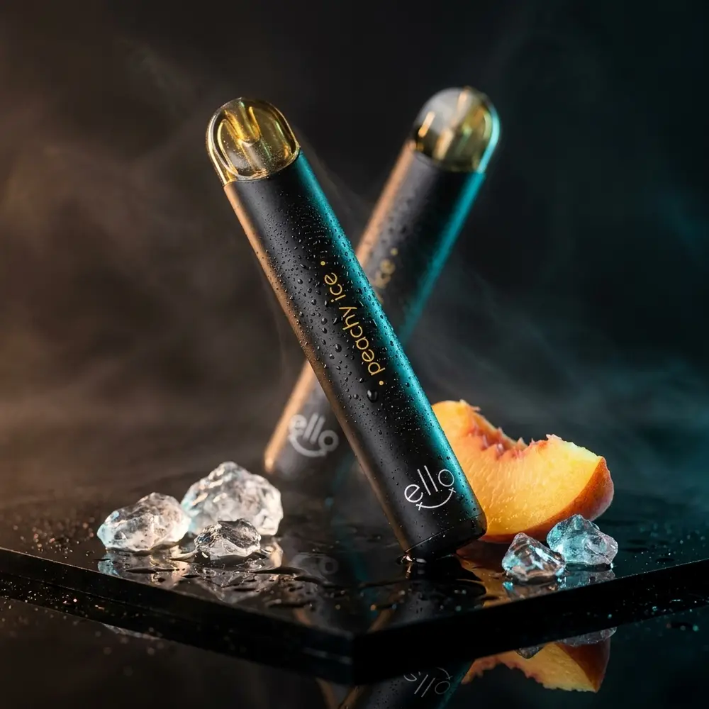 Pod descartavel Blvk Ello Peachy Ice em close sobre acrilico molhado com gelo e pêssego ao lado - Vapor Gringo