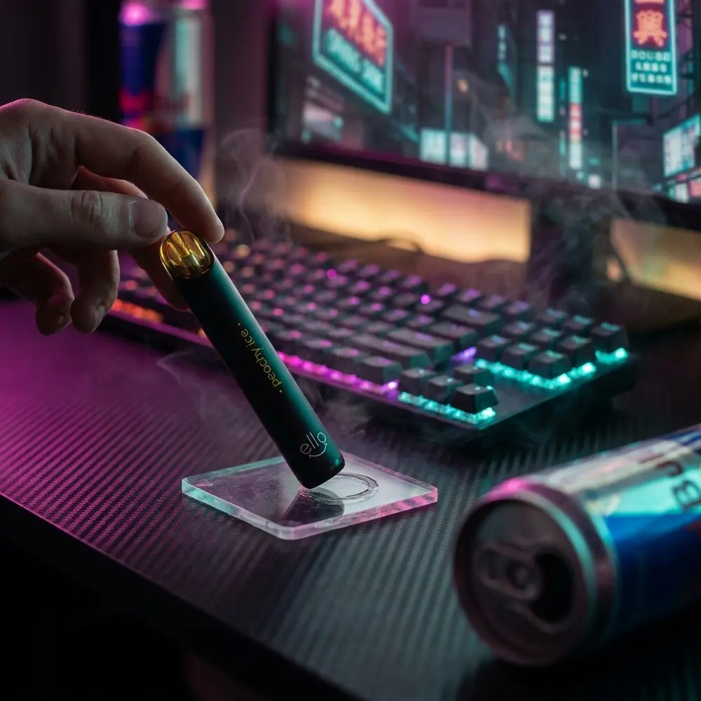 Pod Blvk Ello Peachy Ice apoiado em console RGB em ambiente noturno neon urbano com acessórios - Vapor Gringo