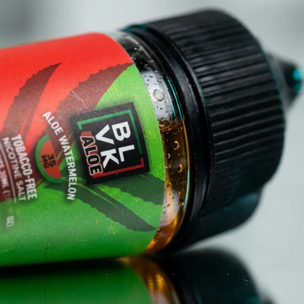 Close-up do rótulo e bico do frasco Blvk Unicorn Salt Aloe Watermelon, gotas de condensação, textura do vidro e microreflexos - Vapor Gringo