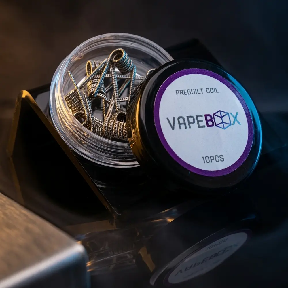 Pack com 10 bobinas Vapebox sobre acrilico preto brilhante com reflexos azuis e luz quente - Vapor Gringo