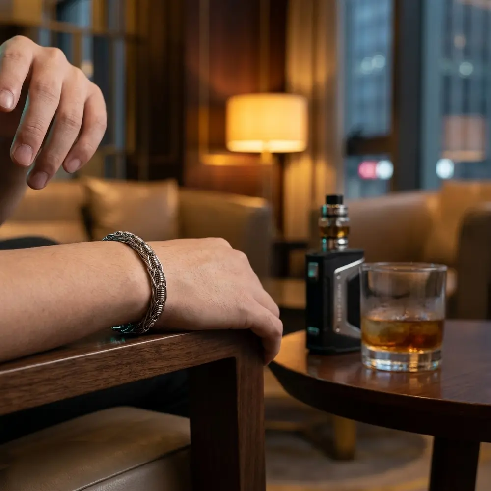 Bracelete Demon Killer no pulso sobre apoio de madeira em lounge moderno com vape e copo ao fundo - Vapor Gringo