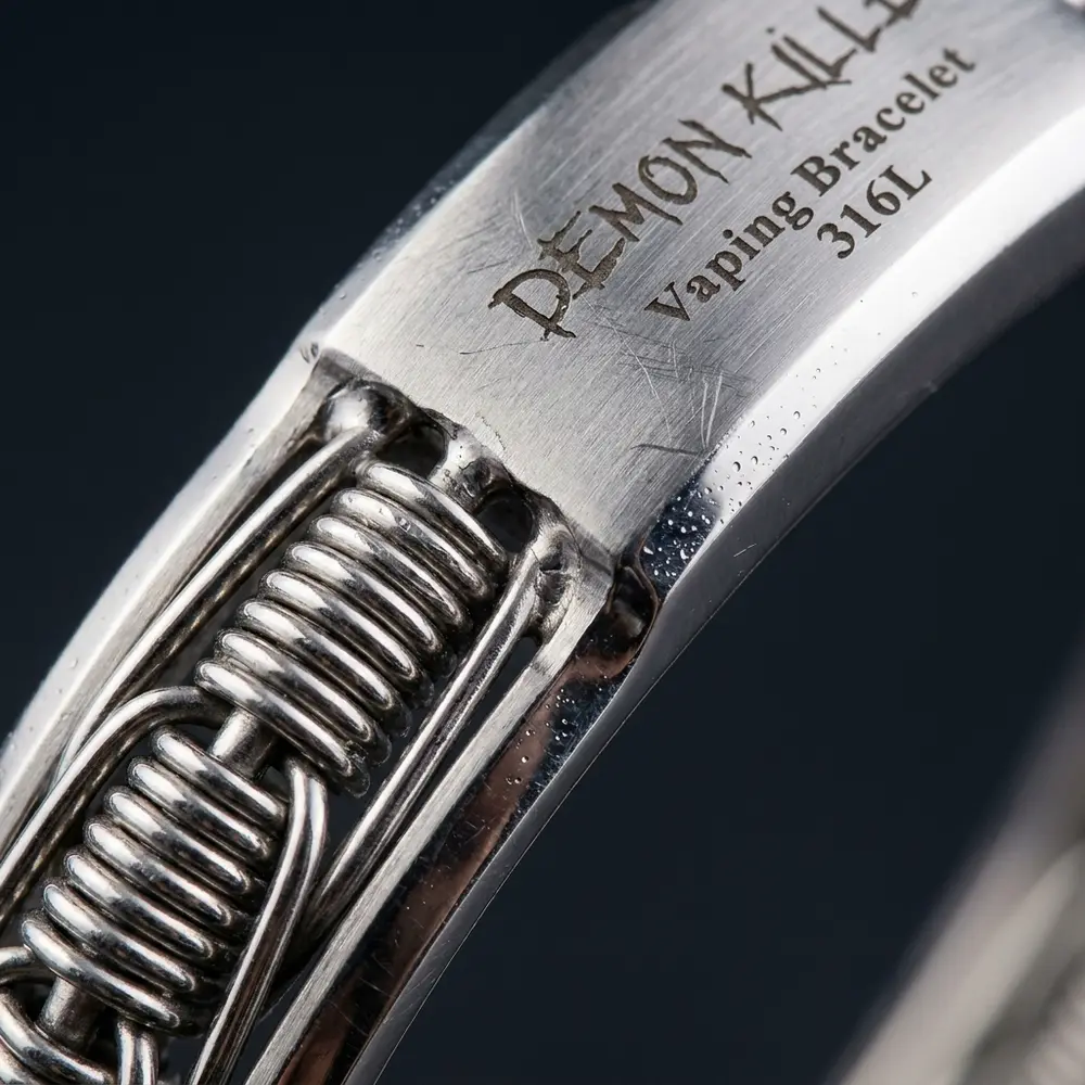 Close-up do bracelete Demon Killer em aço inox mostrando logo, textura escovada e reflexos microdetalhados - Vapor Gringo