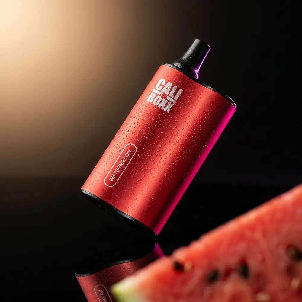 Pod descartável Cali Bars Boxx melancia em close sobre acrílico preto brilhante com gotas e fatia de melancia desfocada - Vapor Gringo