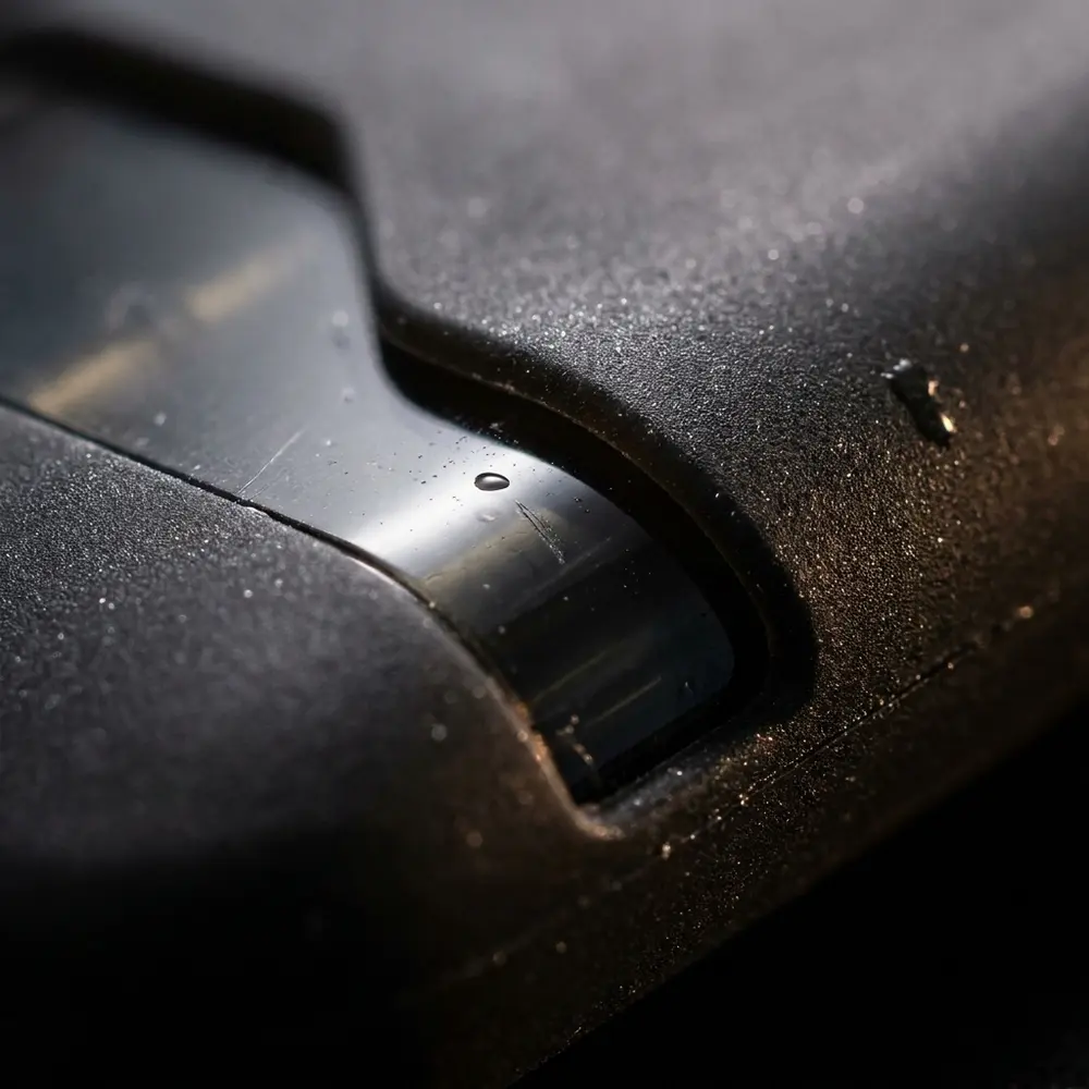 Detalhe da textura da capa de silicone Suorin Air, mostrando logo, costura e gotas sobre a superfície - Vapor Gringo