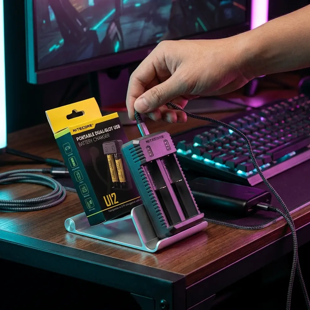Carregador Nitecore UI2 sobre mesa gamer RGB perto de teclado e powerbank com luzes magenta e ciano - Vapor Gringo
