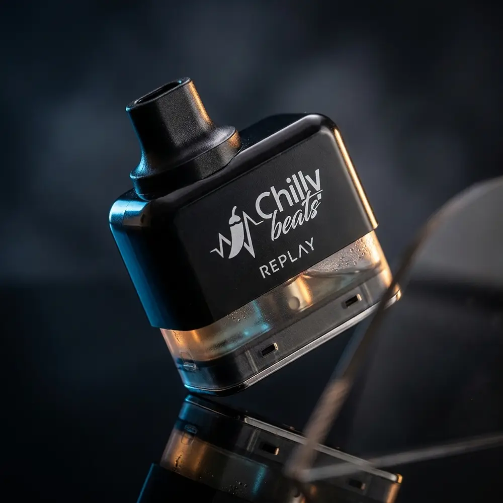 Cartucho Refil Pod Replay Chilly Beats inclinado sobre base acrilica preta, luzes azul e ambra e logo visivel - Vapor Gringo