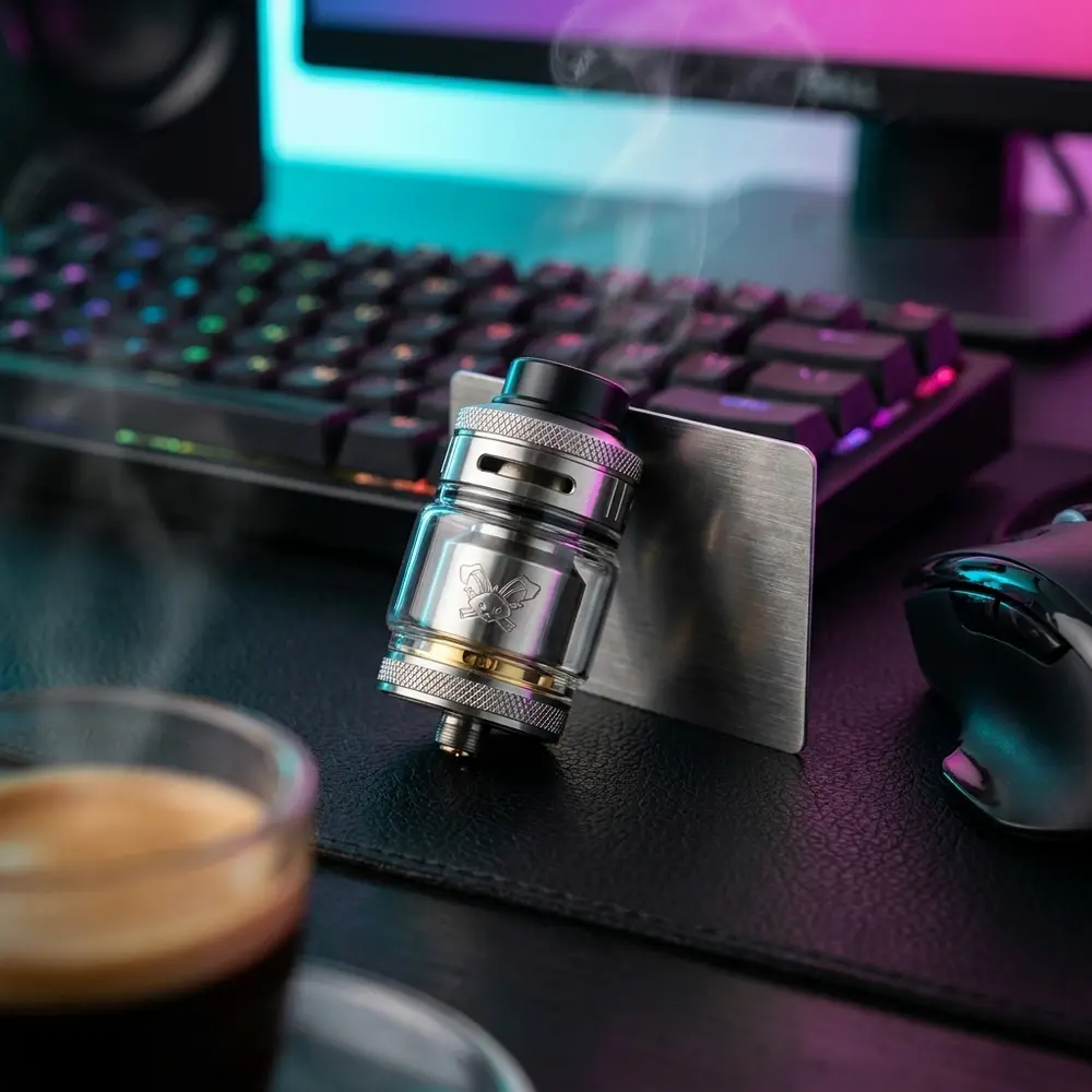 Dead Rabbit V2 RTA HellVape sobre mesa gamer RGB, luzes neon ao fundo e acessórios desfocados - Vapor Gringo