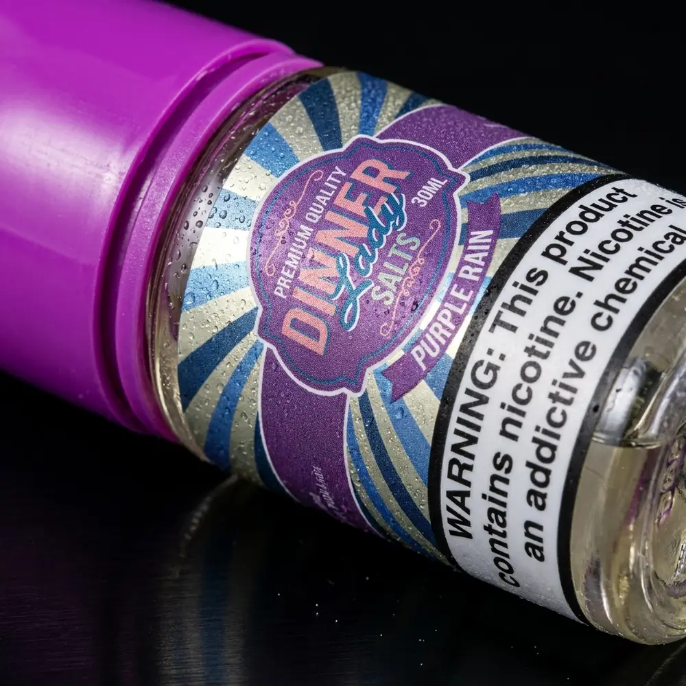 Close-up do rótulo e bico da garrafa Dinner Lady Salt Purple Rain com condensação e textura do rótulo - Vapor Gringo