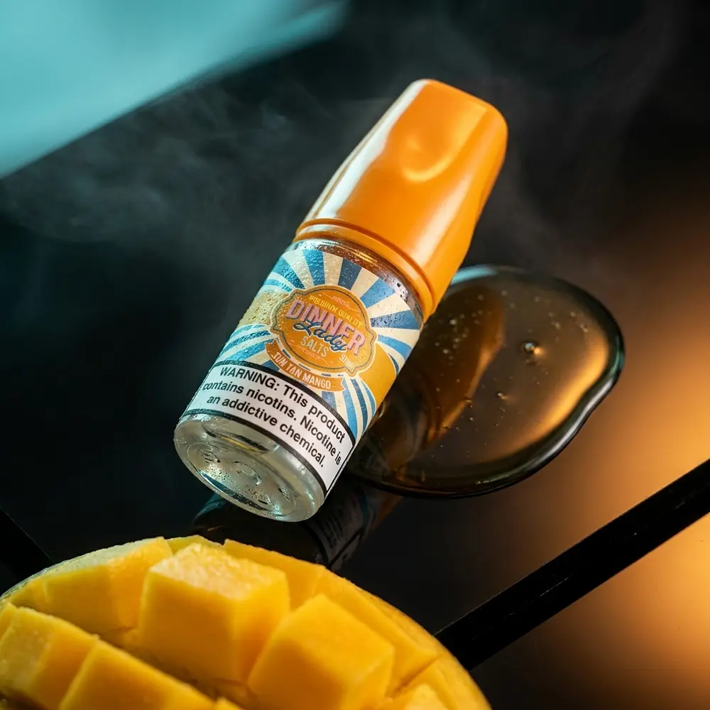 Frasco Dinner Lady Sun Tan Mango 30ml sobre superfície preta brilhante, iluminação dourada e reflexos luxuosos - Vapor Gringo