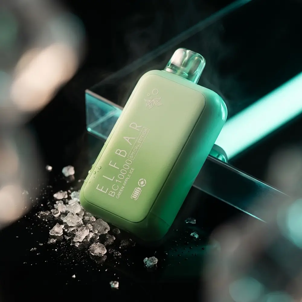 Pod descartável Elf Bar BC10000 Green Apple Ice sobre base acrílica preta com reflexos verdes e gelo picado ao lado - Vapor Gringo