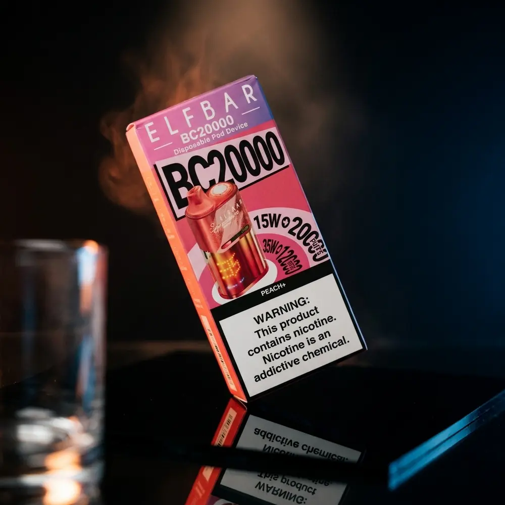 Pod descartavel Elf Bar BC20000 Peach+ suspenso sobre base acrilica preta, luzes quentes e reflexos dramáticos - Vapor Gringo