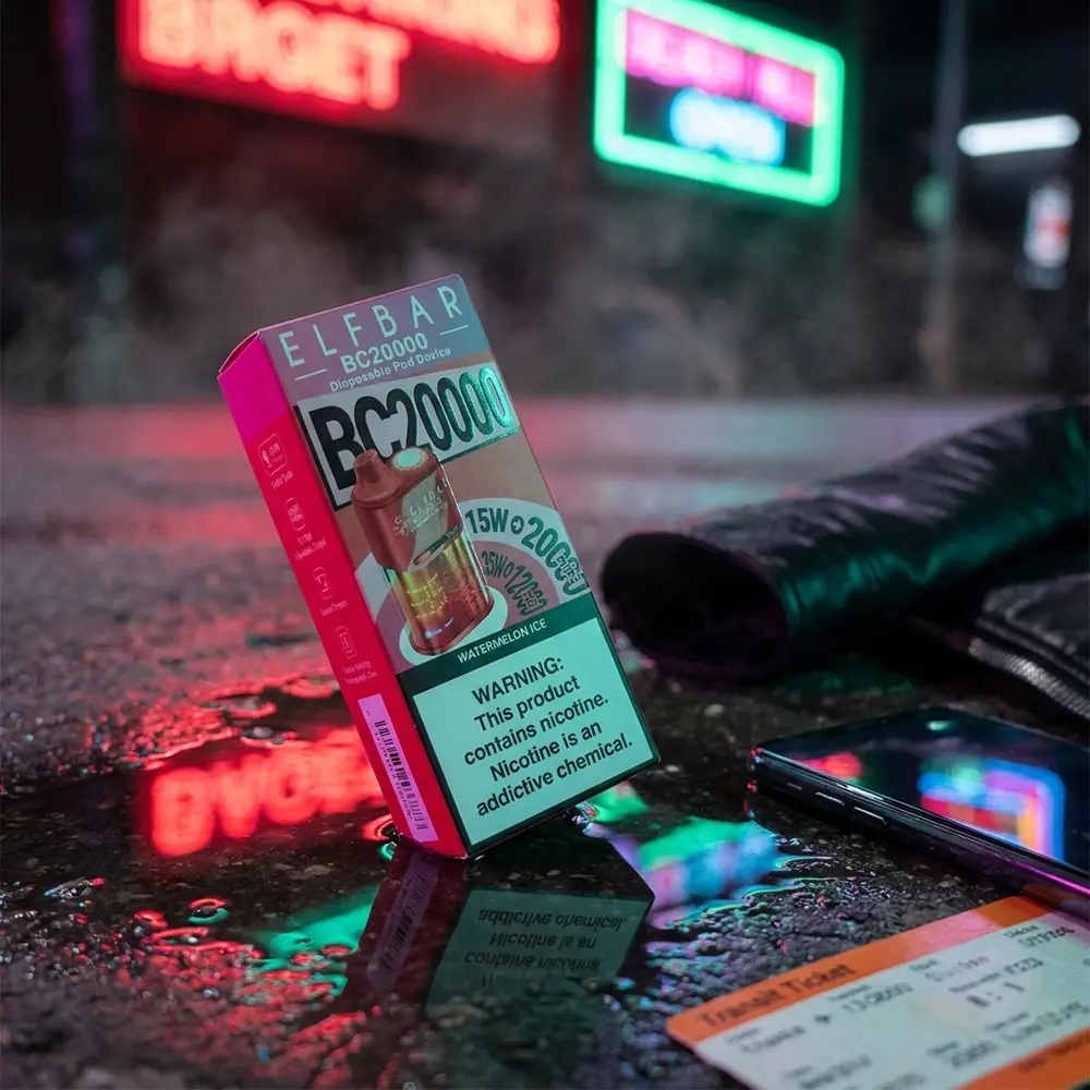 Elf Bar BC20000 Watermelon Ice encostado em calcada molhada com neons urbanos rosa e verde, cena noturna - Vapor Gringo