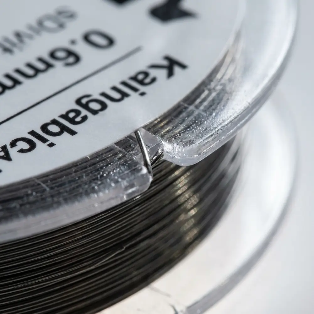Close-up do rótulo e do fio Kanthal A1 0.6mm no carretel Vapebox, textura metálica e reflexos - Vapor Gringo