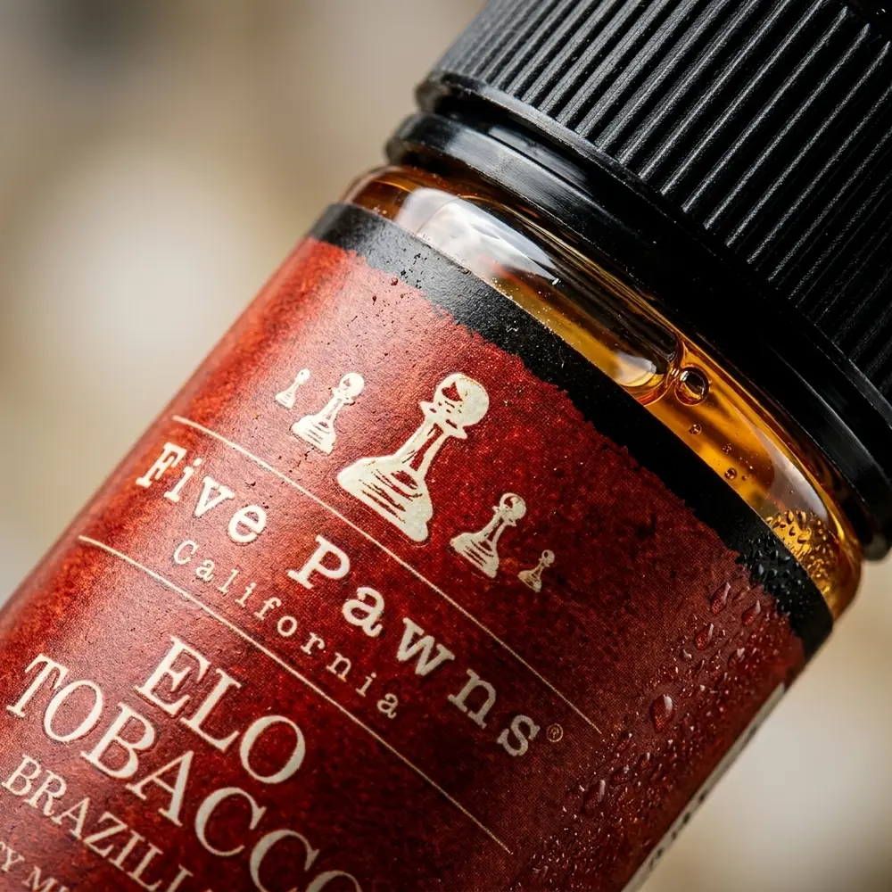 Close-up da etiqueta e bico do Five Pawns Elo Tobacco Brazilian 60ml com gotas de condensação e reflexos metálicos - Vapor Gringo