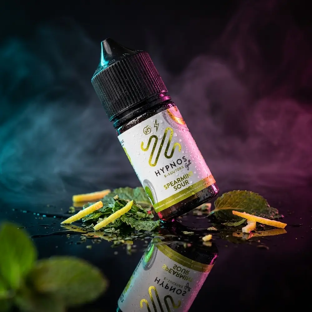 Frasco Hypnos Salt Spearmint Sour com rótulo intacto sobre acrilico brilhante, condensacao e folhas de menta - Vapor Gringo