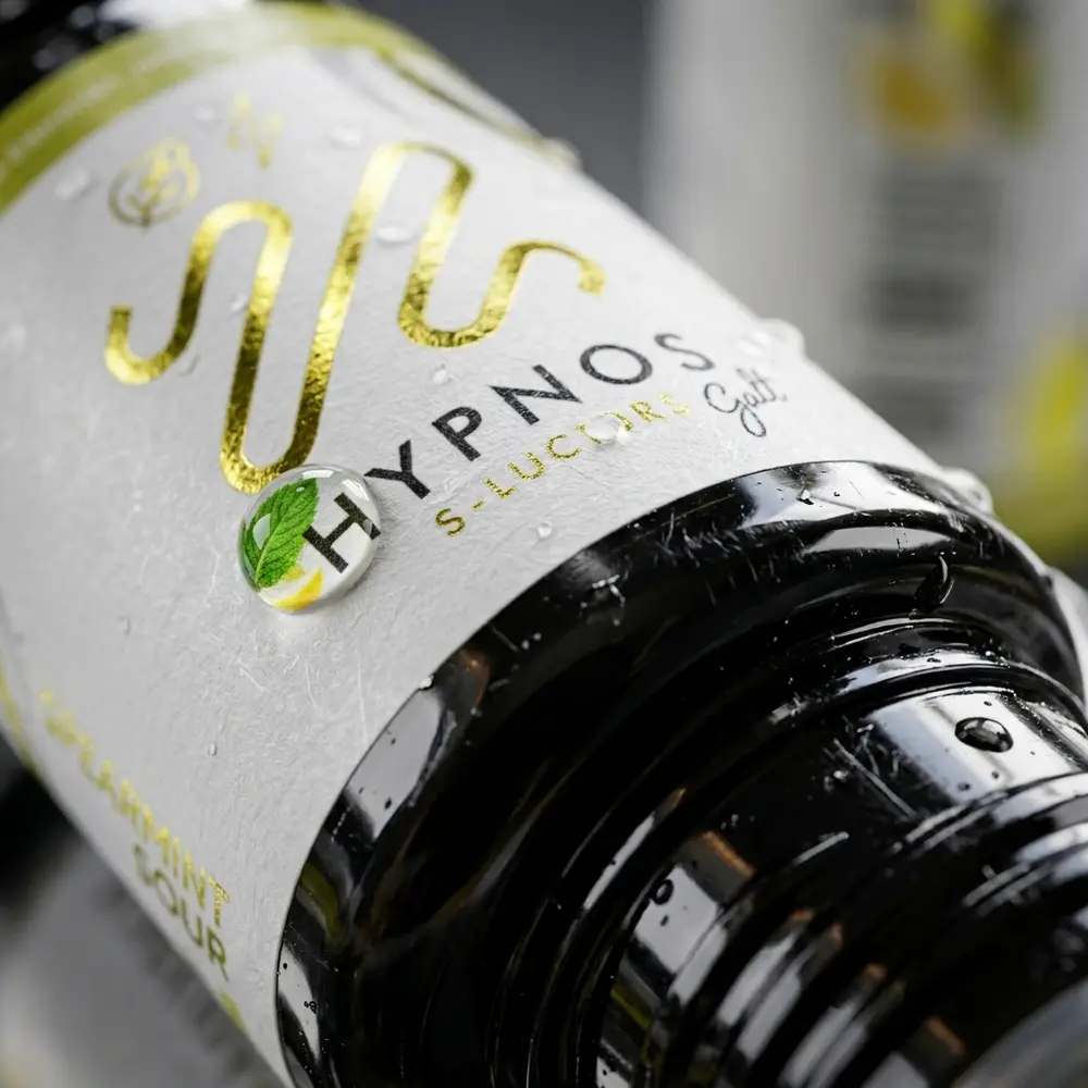 Close do rotulo Hypnos Salt Spearmint Sour mostrando textura, gotas de condensacao e reflexos sutis de menta - Vapor Gringo