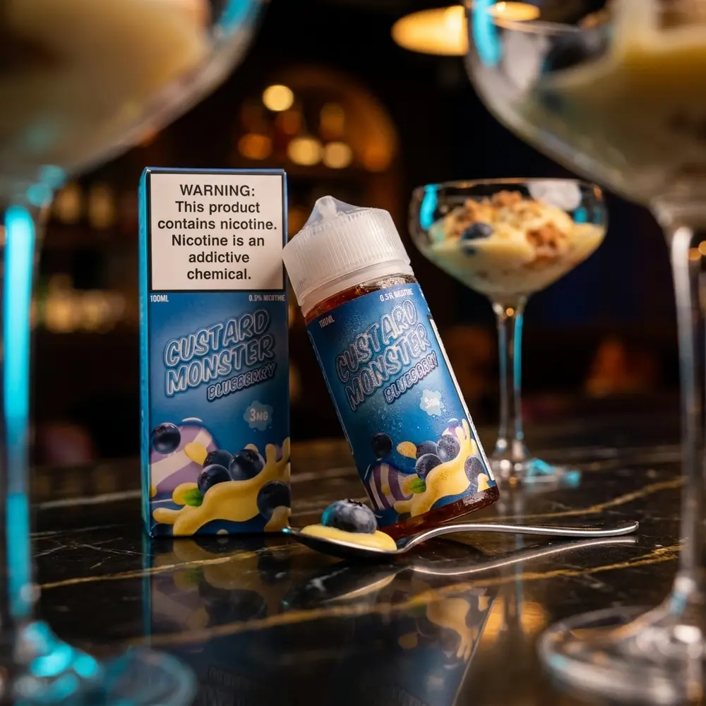 Garrafa Jam Monster Blueberry Custard sobre balcão de lounge urbano com mirtilos e copo de sobremesa ao fundo. - Vapor Gringo