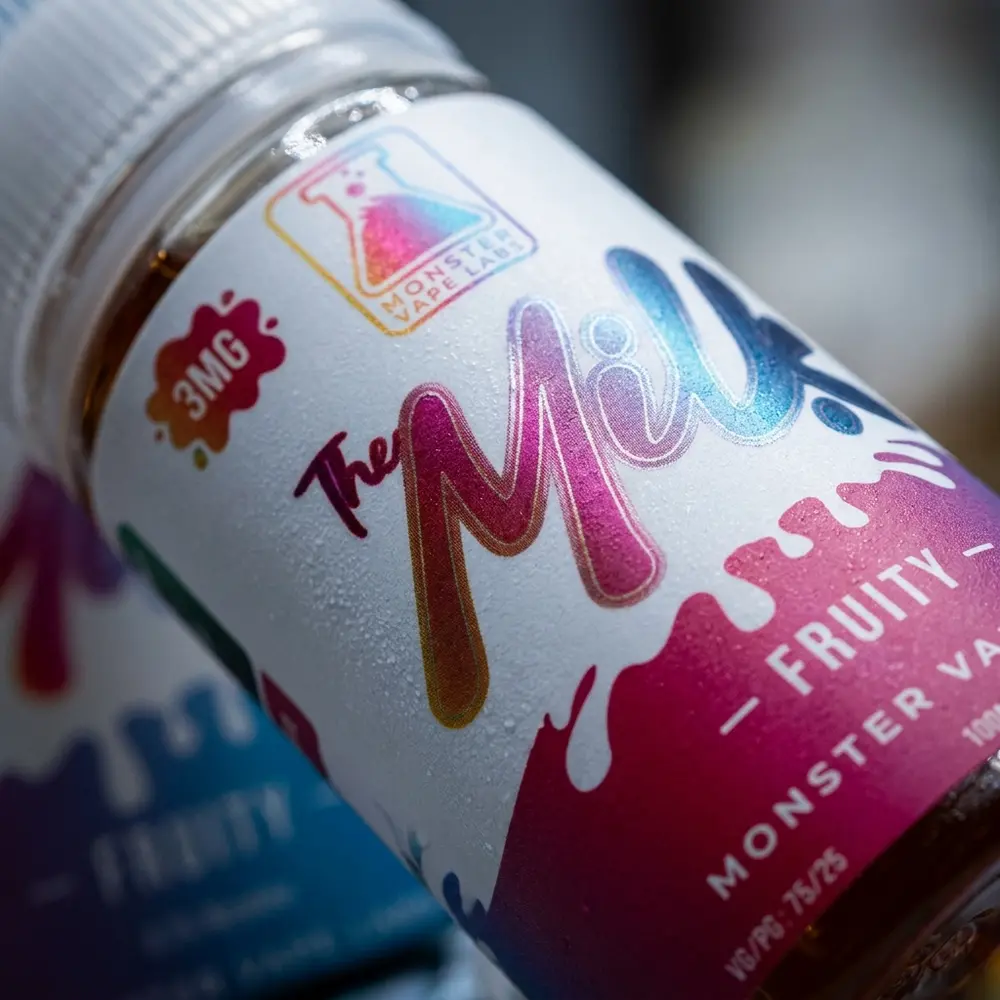 Macro do rótulo Jam Monster The Milk Fruity 100ml mostrando textura, tipografia e gotas de condensação - Vapor Gringo