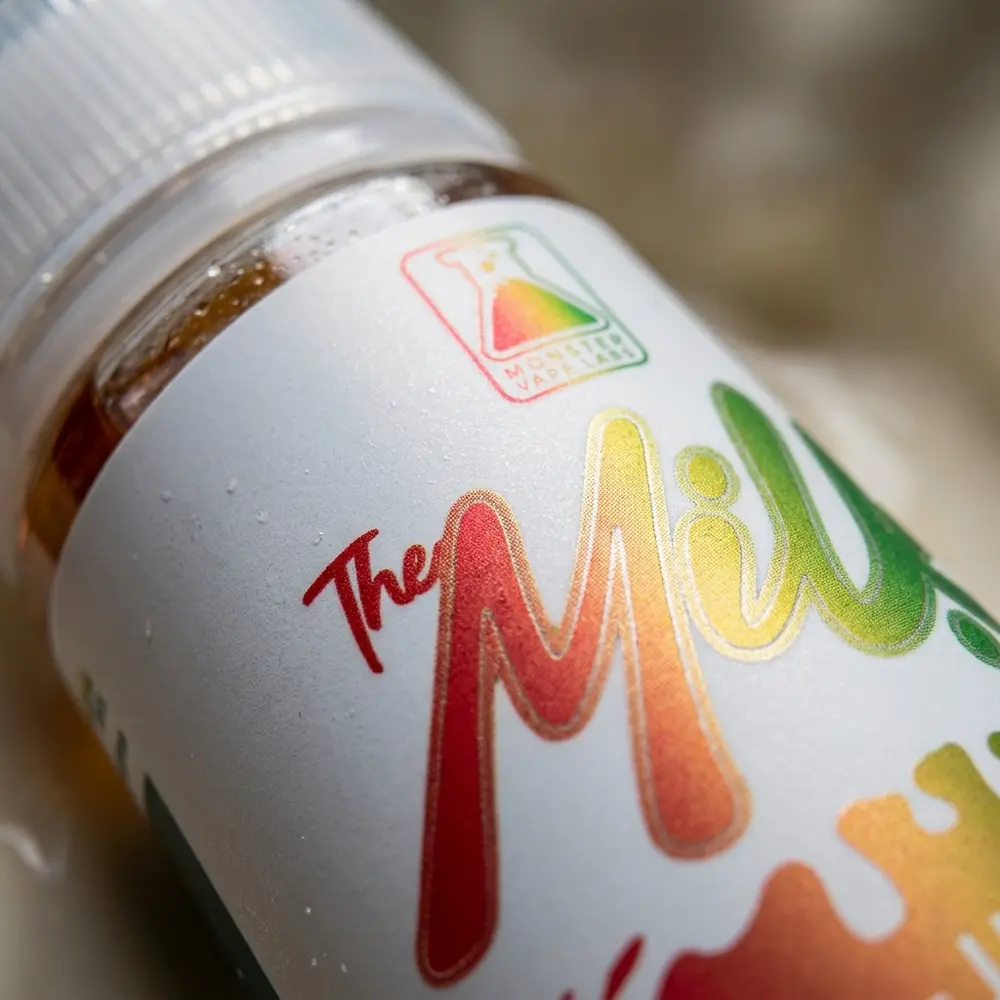 Macro do rotulo Jam Monster The Milk Jax com condensacao, textura do plastico, bico do frasco e reflexos do rotulo - Vapor Gringo