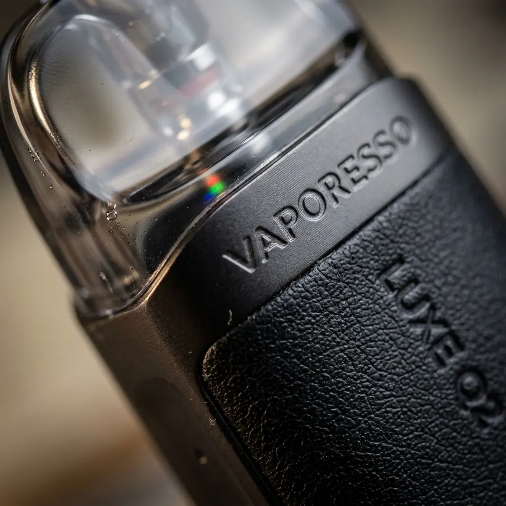 Macro do Kit Pod Luxe Q2 mostrando textura de couro, selo e acabamento metálico em detalhe - Vapor Gringo
