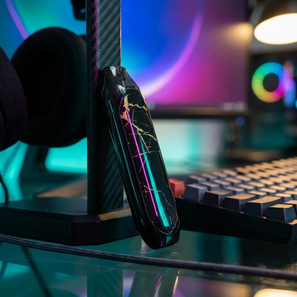 Kit Pod Mino Coilart apoiado em mesa gamer RGB perto de teclado mecânico e fone com reflexos - Vapor Gringo