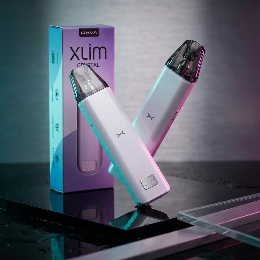 Kit Pod Xlim Crystal - Oxva em close angular sobre base acrilica preta, luzes teal e magenta e reflexos - Vapor Gringo