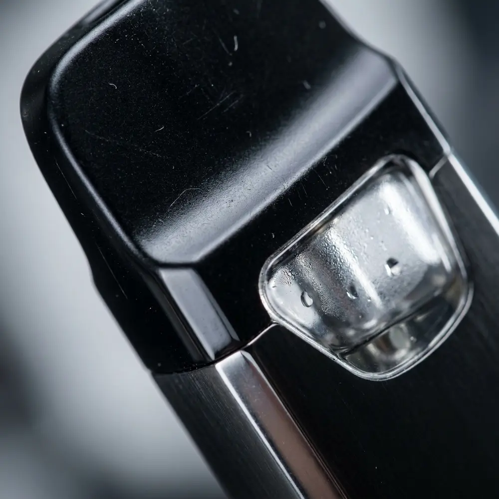 Macro do Kit Pod Yearn Uwell mostrando bocal, janela transparente, acabamento metalico e gotas de condensacao - Vapor Gringo