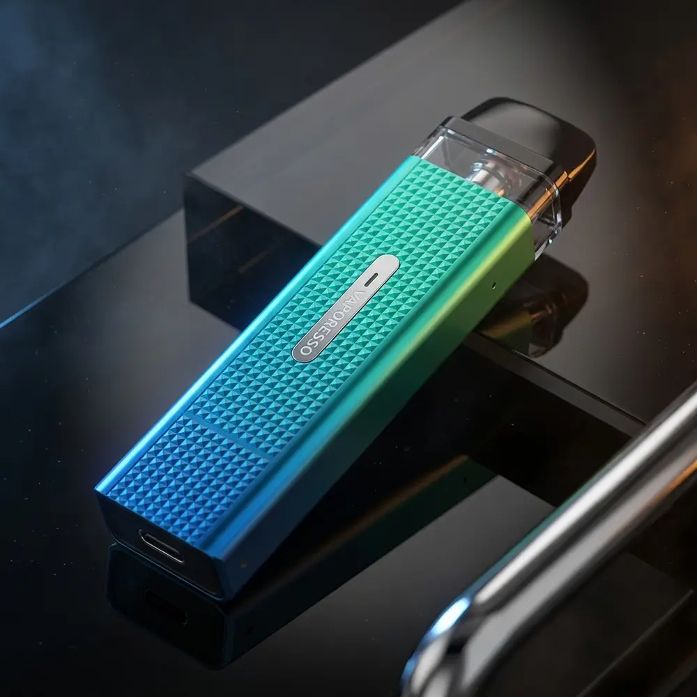 Vaporesso Xros Mini apoiado diagonalmente sobre acrílico brilhante, iluminação azul-âmbar e reflexos do chassi - Vapor Gringo