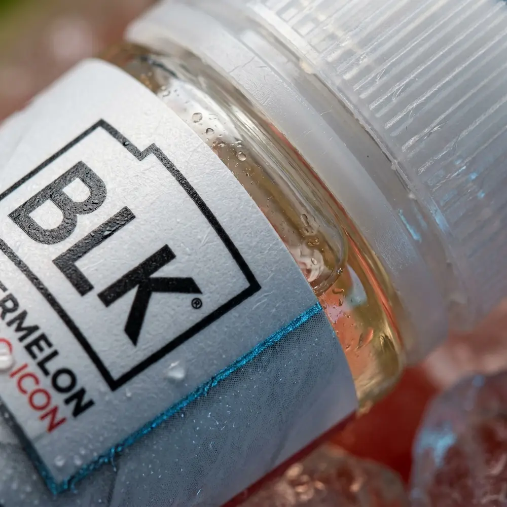 Close-up do rótulo e bico da garrafa BLVK Salt Plus Watermelon Ice com condensação e reflexos detalhados - Vapor Gringo