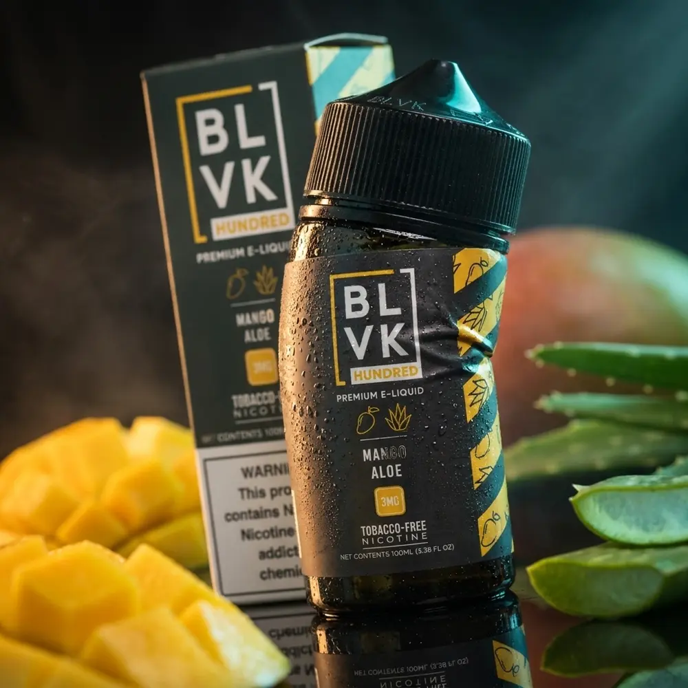 Garrafa Liquido Blvk Unicorn Mango Aloe 100ml sobre acrilico preto com iluminação dramática e mangas desfocadas. - Vapor Gringo