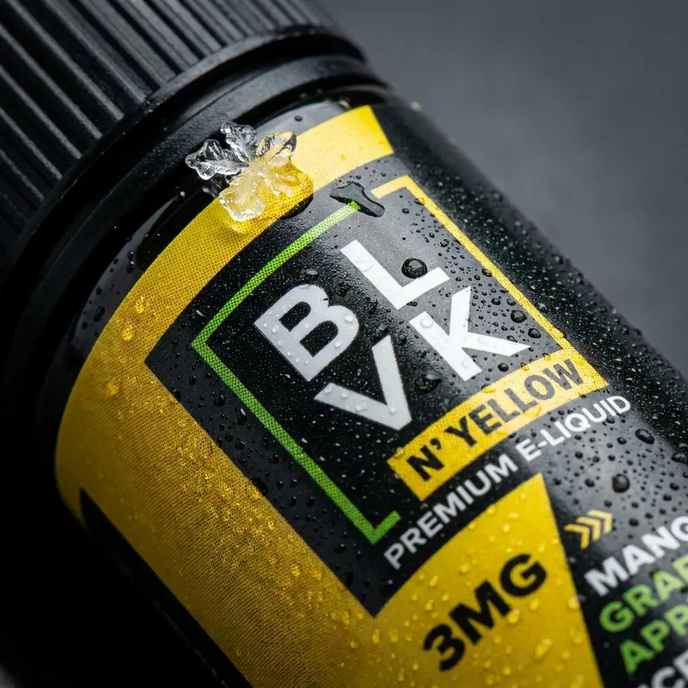 Close-up do rótulo e bico do frasco Blvk Unicorn Yellow com gotas de condensação e reflexos - Vapor Gringo