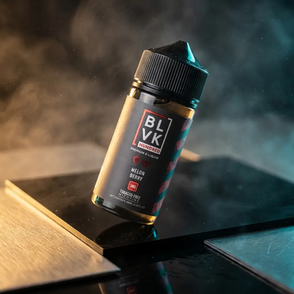 Frasco 100ml Blvk Unicorn Melon Berry sobre base acrílica preta, iluminação dramática e reflexos metálicos - Vapor Gringo