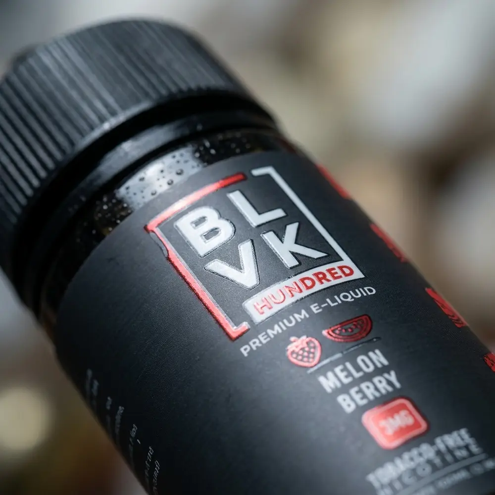 Macro do rótulo Blvk Unicorn Melon Berry 100ml com gotas de condensação, textura do vidro e tipografia nítida - Vapor Gringo