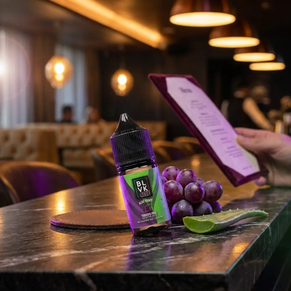 Garrafa Liquido Blvk Unicorn Salt Aloe Grape em balcão de lounge urbano com uvas, folha de aloe e luzes neon - Vapor Gringo