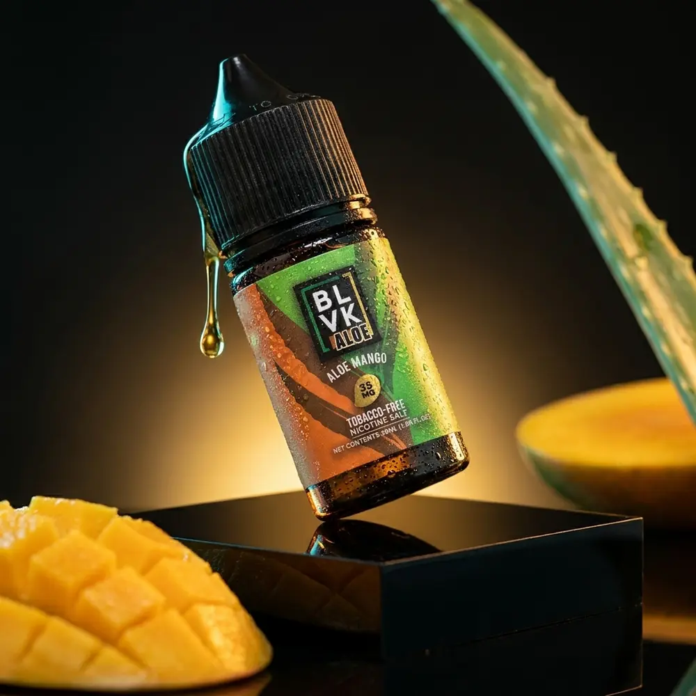 Garrafa Blvk Unicorn Salt Aloe Mango em pedestal acrilico escuro com gotas e luzes quentes e frias - Vapor Gringo