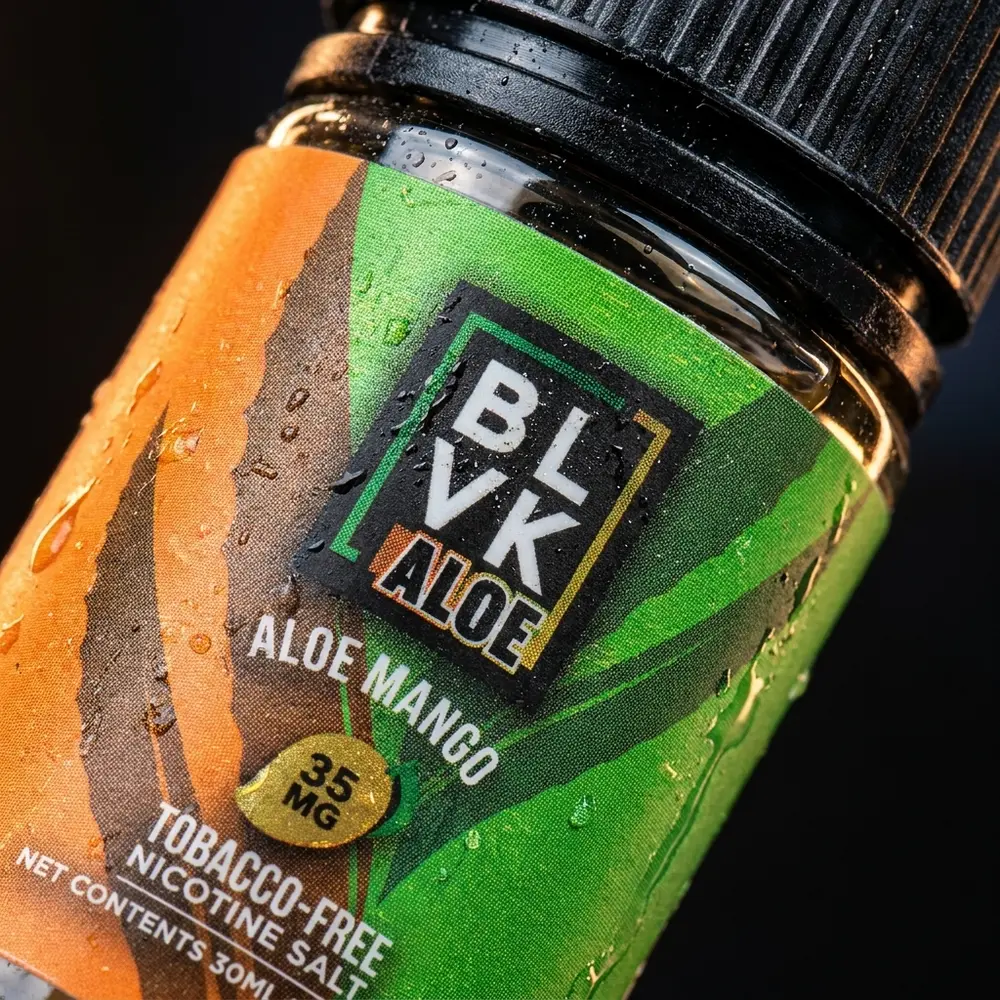 Close-up do rótulo e bocal do Blvk Unicorn Salt Aloe Pineapple com gotas, textura do vidro e reflexos - Vapor Gringo