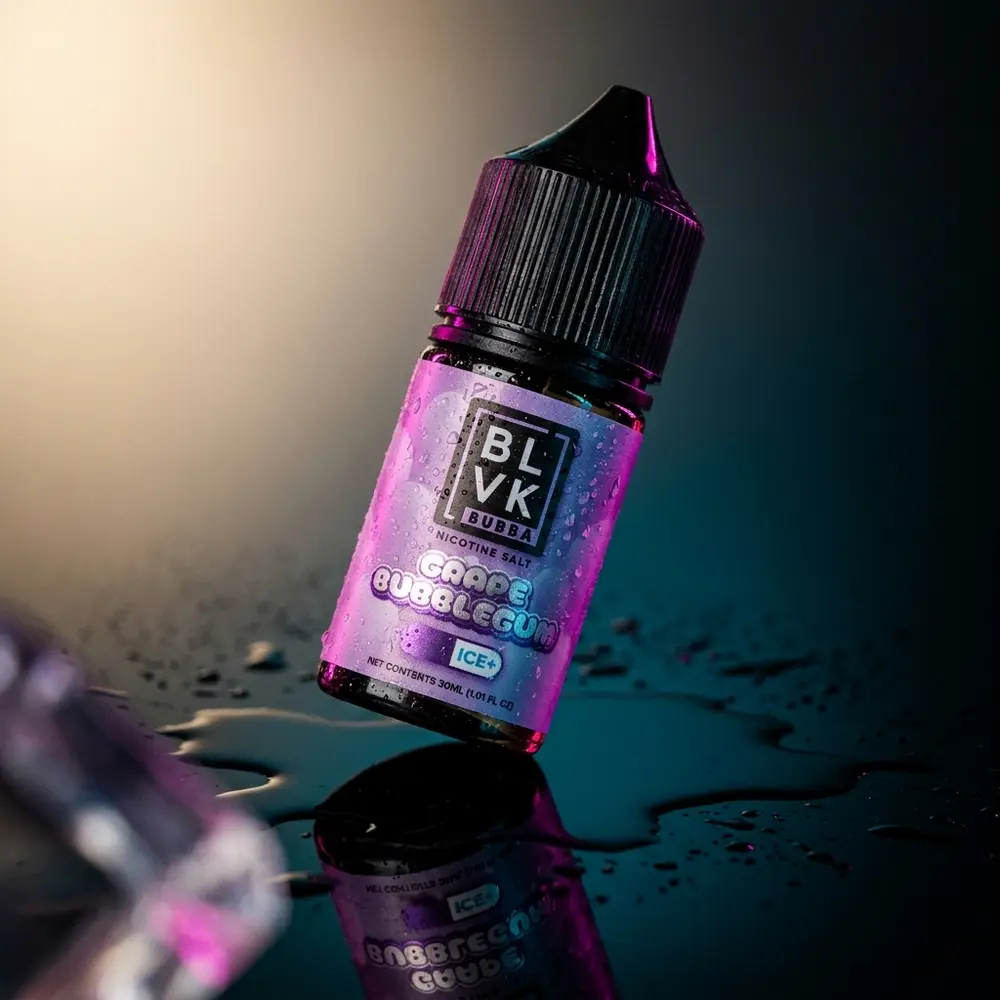 Frasco de liquido BLVK Unicorn Salt Grape Bubblegum Bubba sobre acrilico molhado com iluminacao roxa e azul - Vapor Gringo