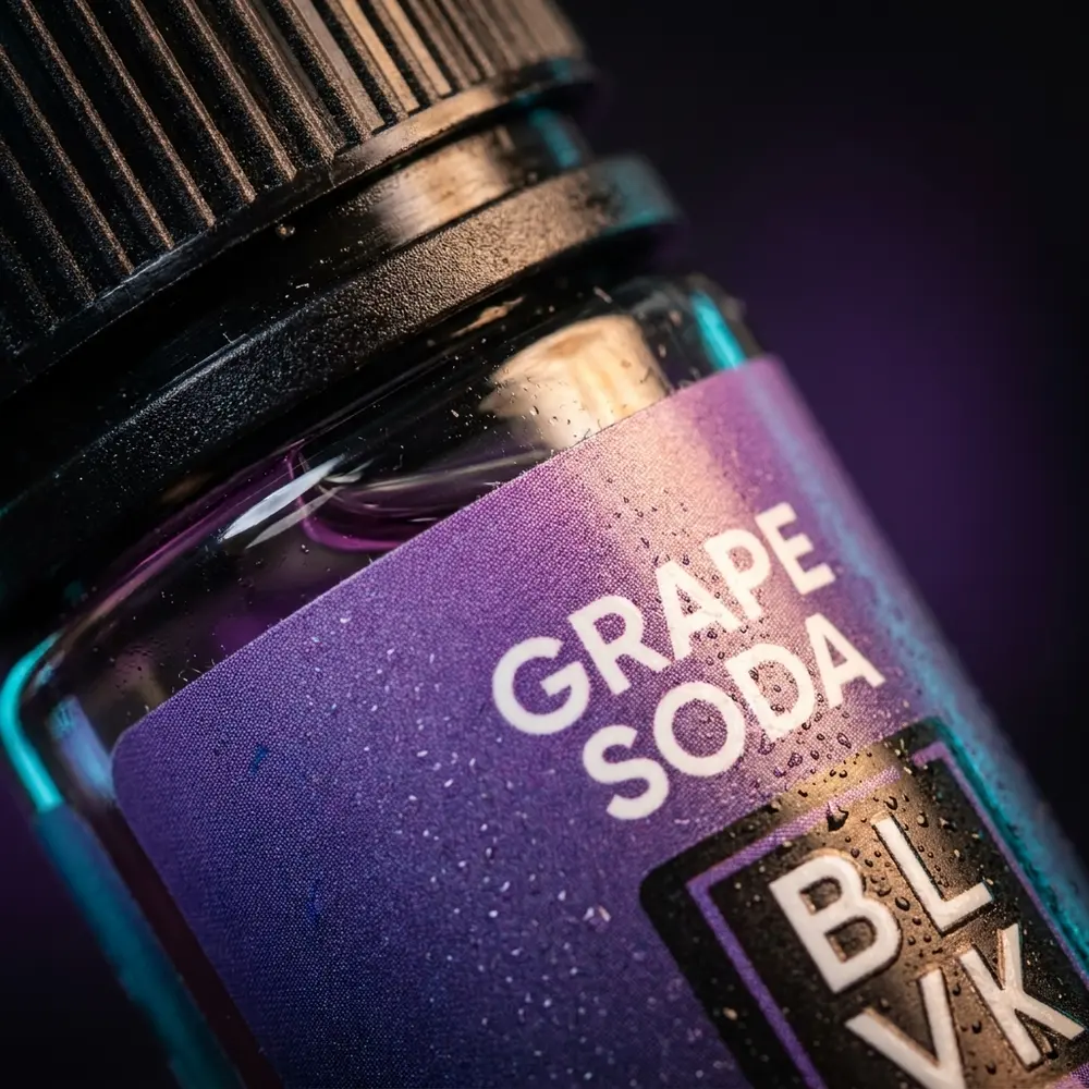 Close-up do rótulo e bico do Líquido BLVK Unicorn Salt, gotas de condensação e micro-reflexos violetas - Vapor Gringo