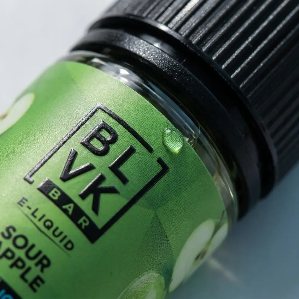 Close macro do rótulo e bico do Líquido BLVK Unicorn Sour Apple Ice, detalhes do rótulo e gotículas visíveis - Vapor Gringo