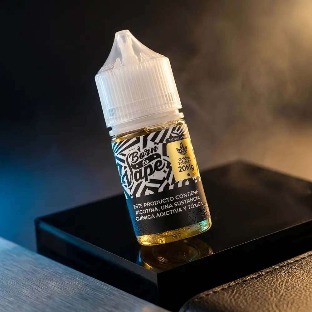 Garrafa Born to Vape Salt Golden Tobacco em estúdio escuro com reflexos dourados e superfície molhada - Vapor Gringo