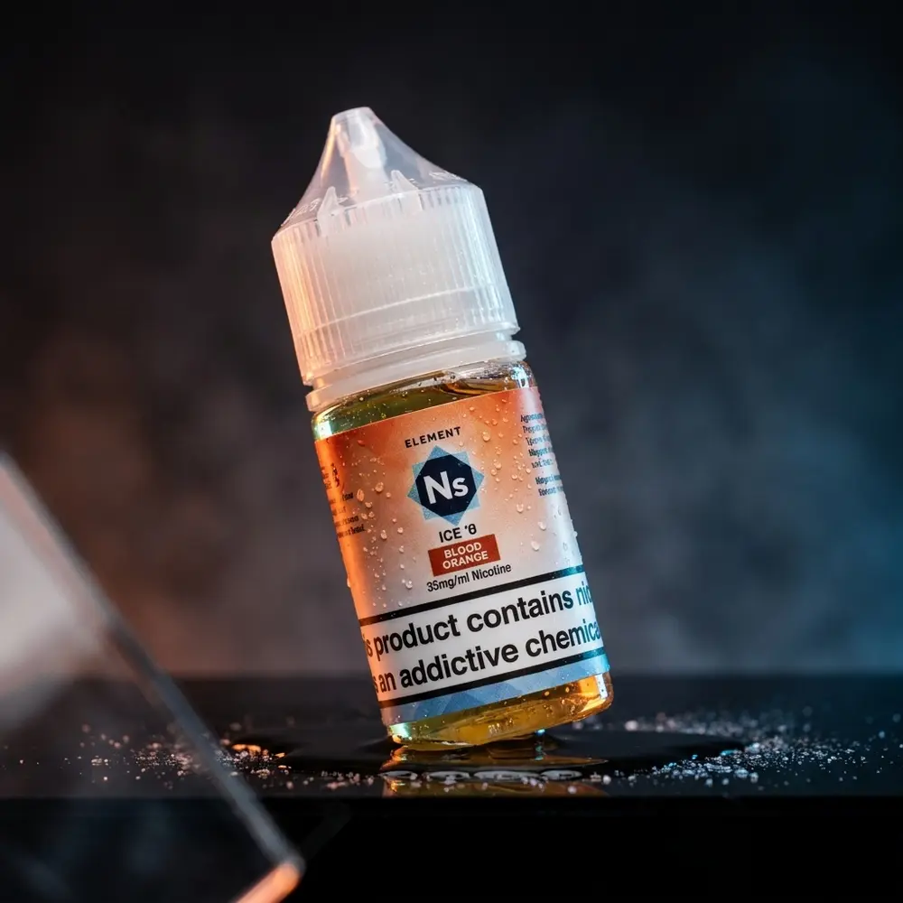 Frasco 30ml Líquido Element Salt Blood Orange Ice sobre acrílico preto com gotas, reflexos e luzes laranja e azul - Vapor Gringo