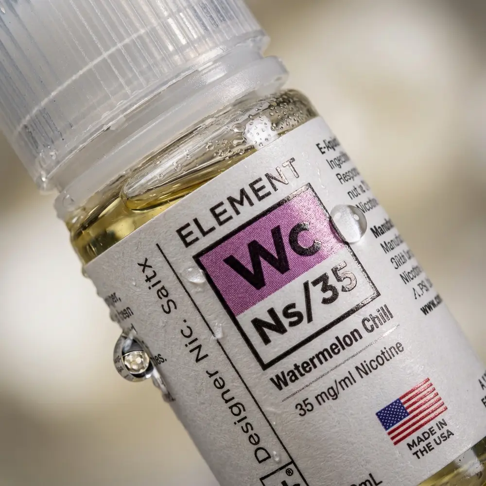 Detalhe do rótulo e bico do liquido Element Salt Watermelon Chill com gotas de condensacao e reflexos nítidos - Vapor Gringo