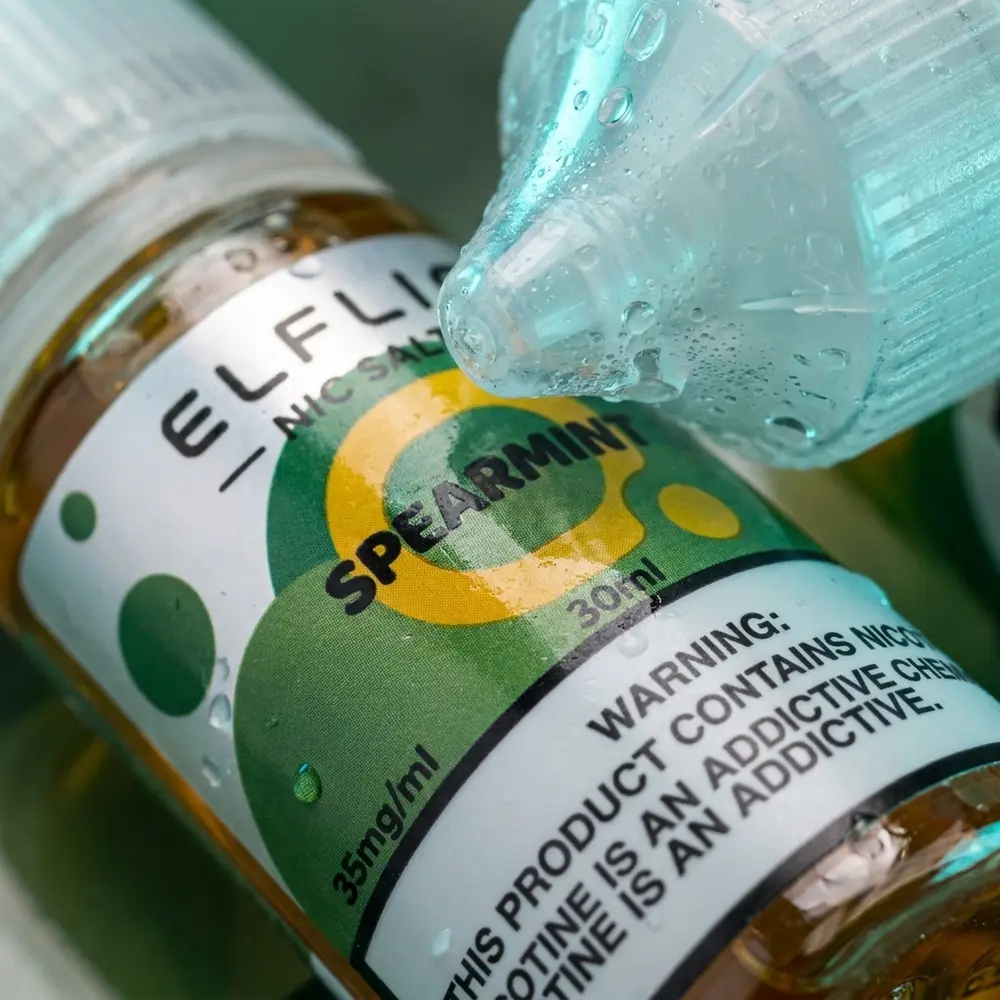 Close-up do rótulo e bico da garrafa Elf Liq Salt Spearmint com gotas de condensação e reflexos nítidos - Vapor Gringo