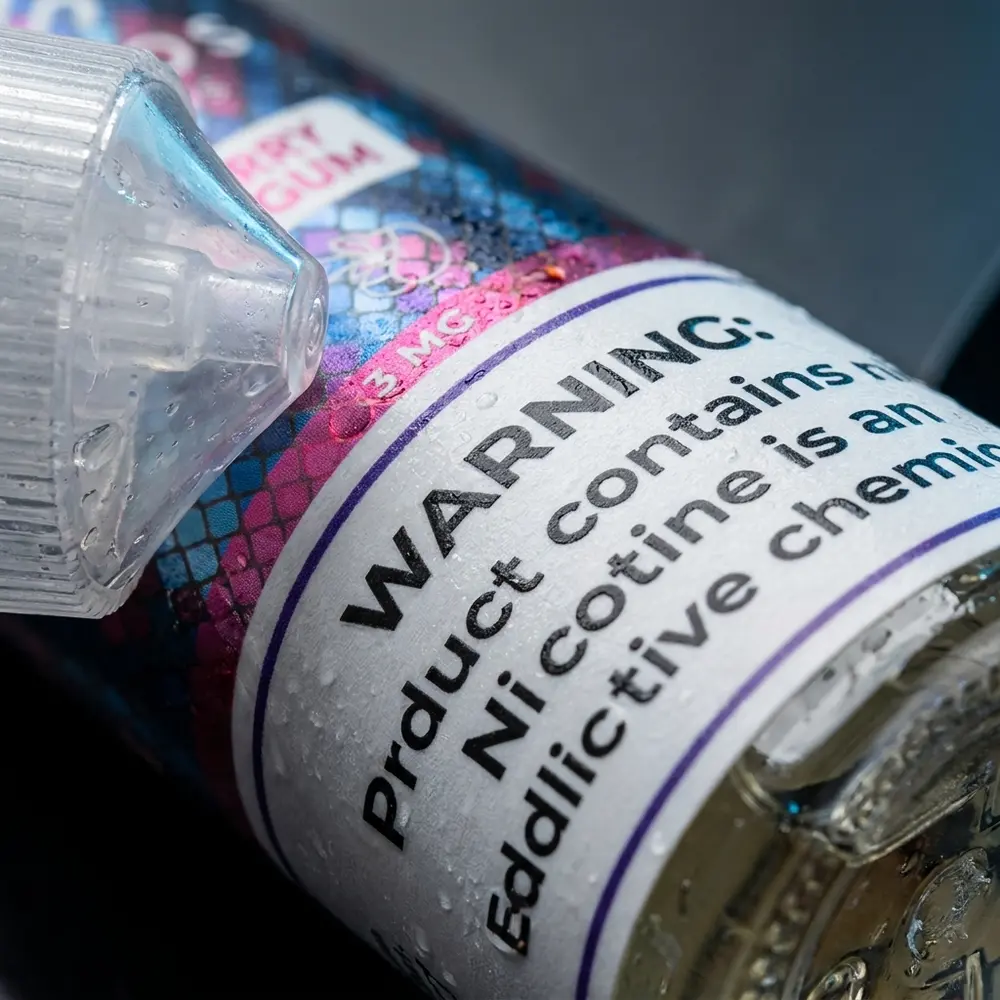 Detalhe macro do rótulo Líquido Hypnos Blueberry Bubblegum com gotas, textura do papel e reflexos realistas - Vapor Gringo