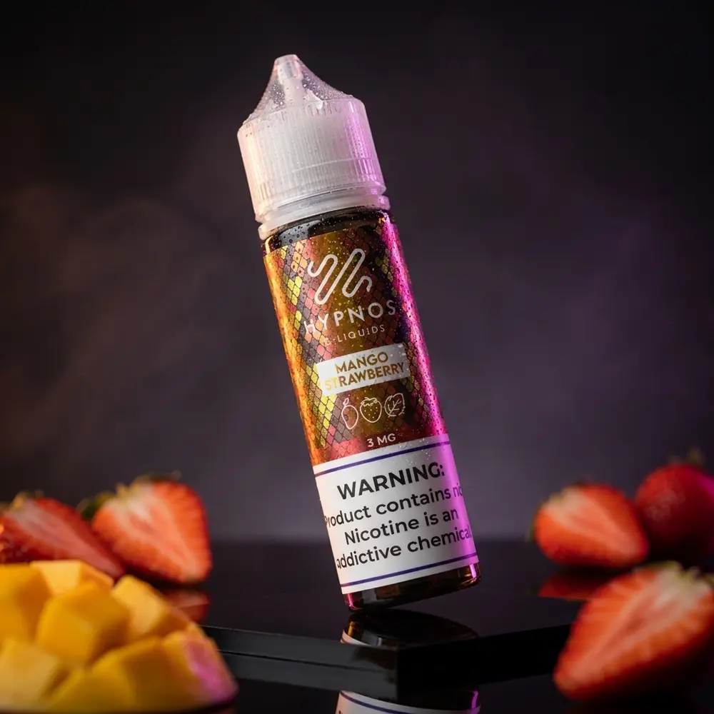 Frasco Líquido Hypnos Mango Strawberry com rótulo original, gotas de condensação e fatias de manga e morango desfocadas em estúdio escuro - Vapor Gringo